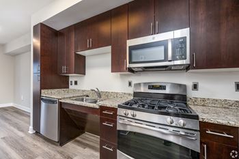 A modern kitchen with dark wood cabinets and stainless steel appliances.